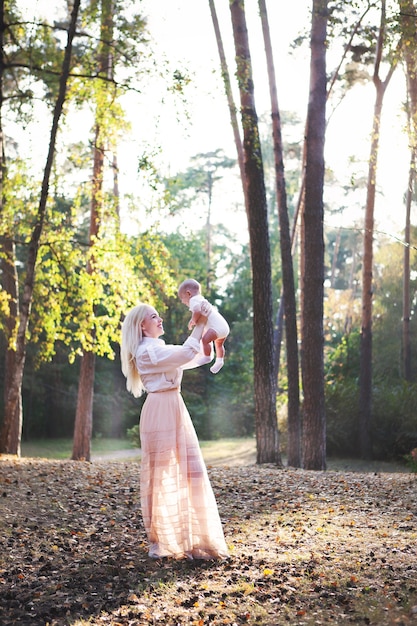 mother playing with little child in park beautiful blonde hair mom holding baby in nature landscape