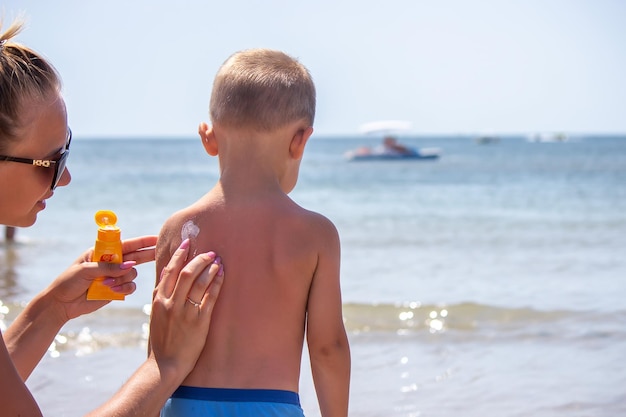 Mother puts cream on her son's back Caring for baby skin Sunscreens in the travel