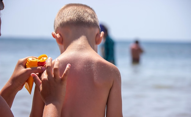 Mother puts cream on her son's back Caring for baby skin Sunscreens in the travel