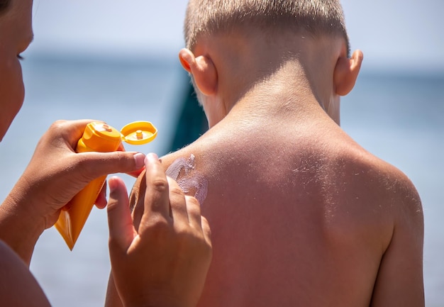 Mother puts cream on her son's back Caring for baby skin Sunscreens in the travel