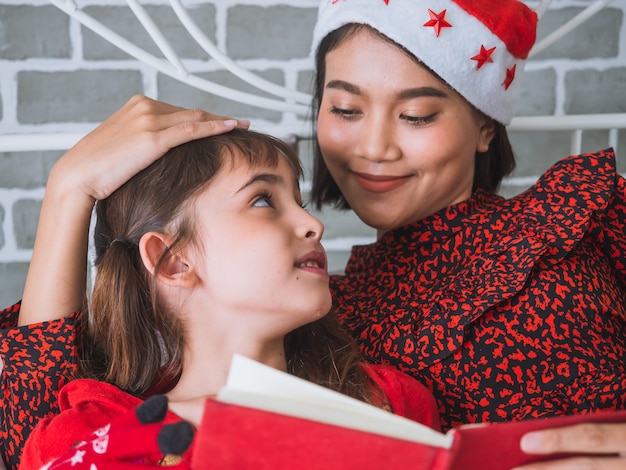 Mother read a book to her daughter on Christmas day,happy family concept