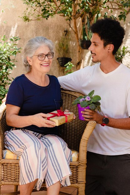 Mother's Day Caucasian mother and her black son with gift in the house garden Happy interracial family