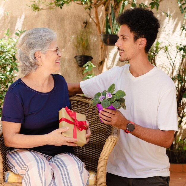 Mother's Day Caucasian mother and her black son with gift in the house garden Happy interracial family