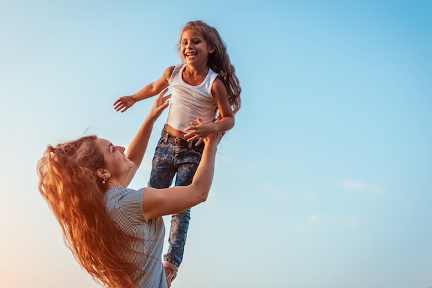 Mother's day. Woman playing having fun with daughter in spring park. Mother tossing girl outdoors and laughing. Family