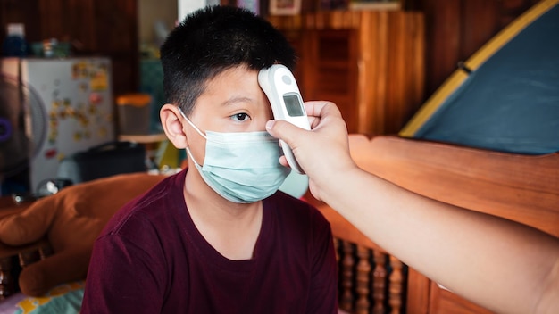 A mother's hand using an infrared thermometer measures the body temperature