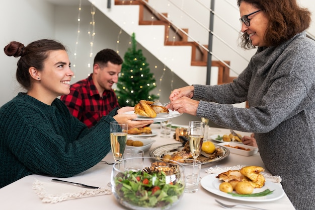 Mother serves daughter piece of roasted chicken Christmas family dinner Holiday