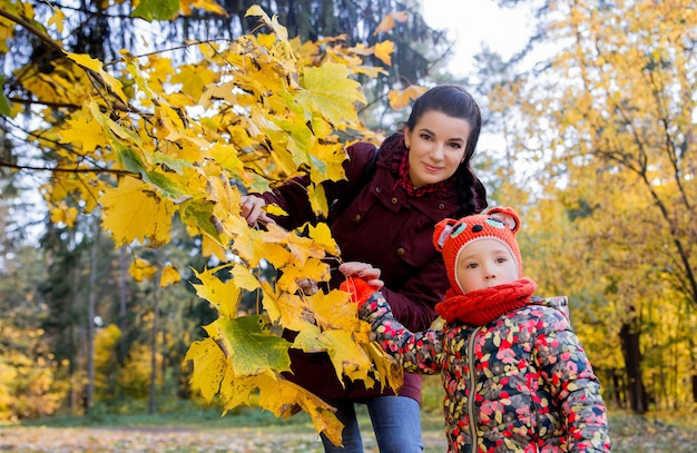 Mother shows her daughter autumn leaves