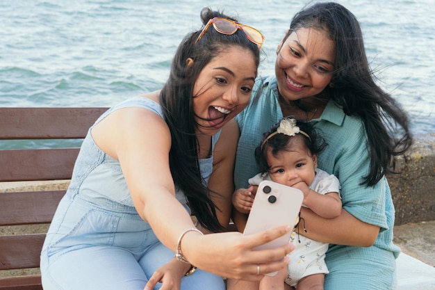 Mother and sister taking a selfie with her baby