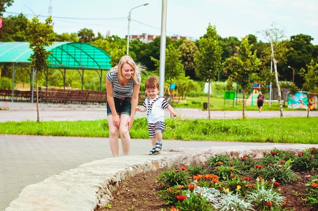 Mother, son are playing in playground, laughing on summer walk. sunny day.  Family holiday. Kids