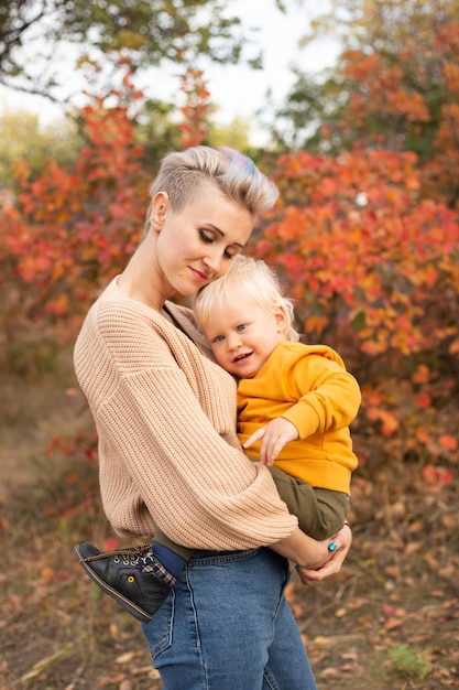 Mother and son in autumn background with golden trees