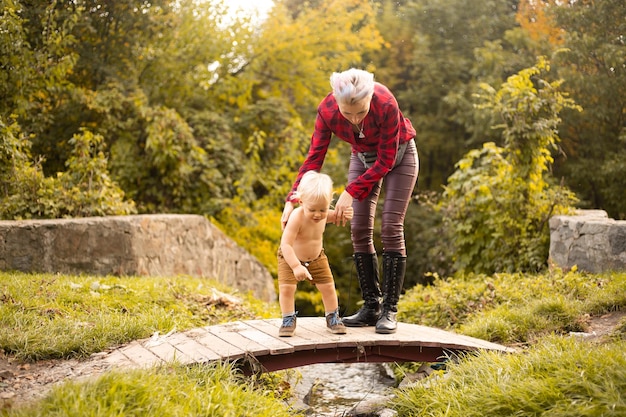 Mother and son on bridge in autumn background with golden trees