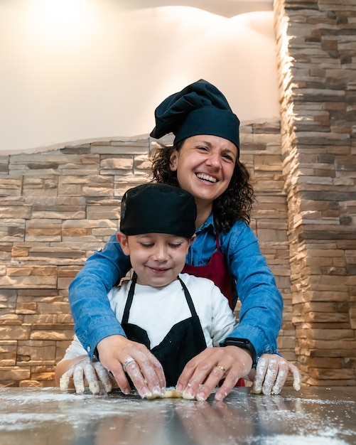 Mother and son cooking a pastry together in chef's costumes