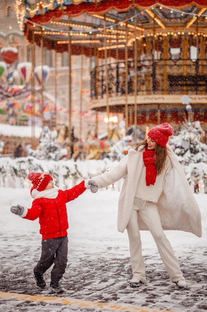 Mother and son have fun at the Christmas market on the background of the carousel