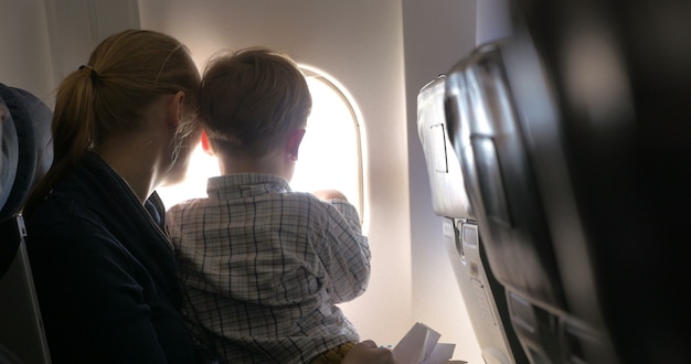 Mother and son looking out illuminator in plane