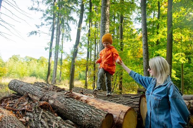 Mother and son playing on logs in a forest