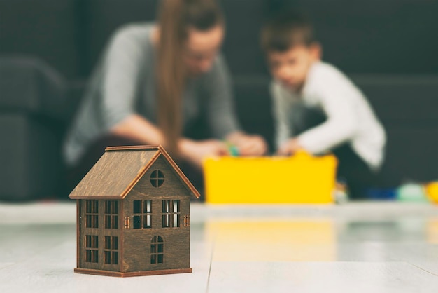 Mother and son playing together on the background of wooden toy house