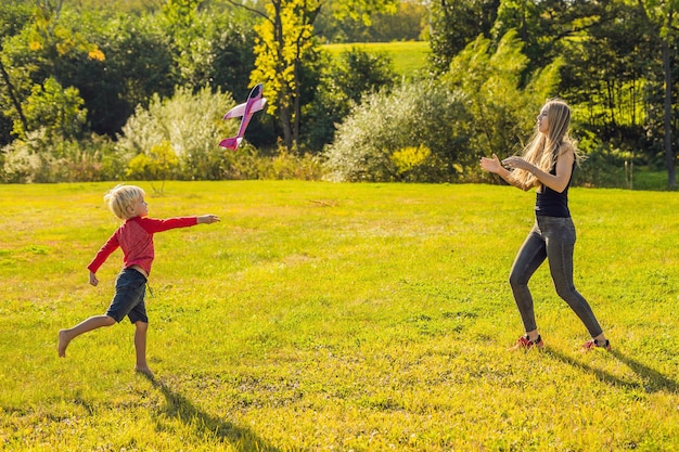 Mother and son playing with a large model toy aeroplane in the park.