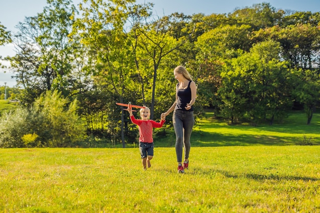 Mother and son playing with a large model toy aeroplane in the park.