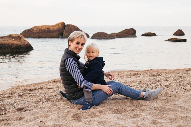 Mother and son sitting on the beach playing in autumn time