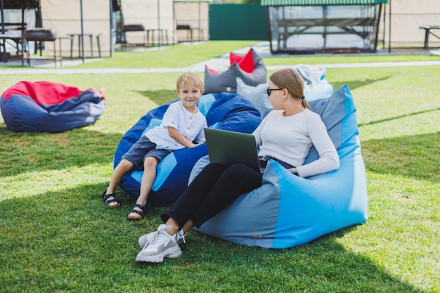 Mother and son on a soft bean bag chair Mom and son in a bag chair in nature