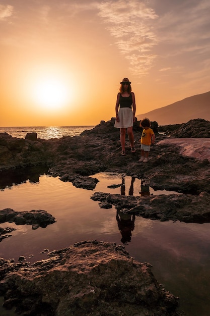 Mother and son at sunset on the beach of Tacoron on El Hierro Canary Islands vacation concept orange sunset