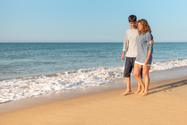 Mother and son talking and walking on the beach