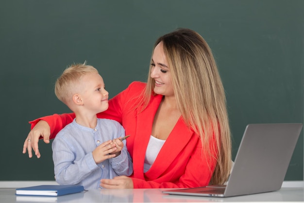 Mother and son together using computer laptop school child learning education online lesson teacher