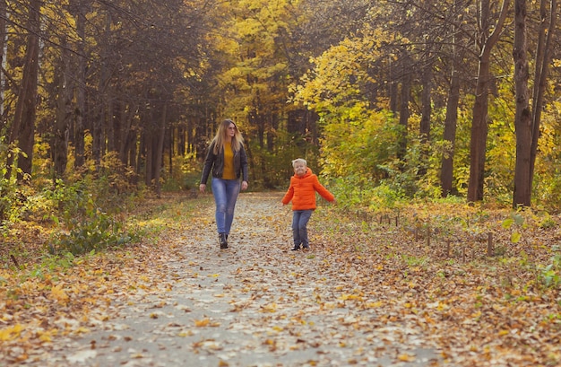 Mother and son walking in the fall park and enjoying the beautiful autumn nature season single paren