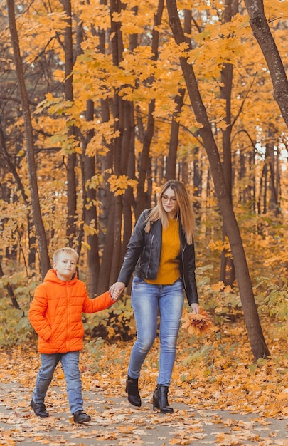 Mother and son walking in the fall park and enjoying the beautiful autumn nature season single paren