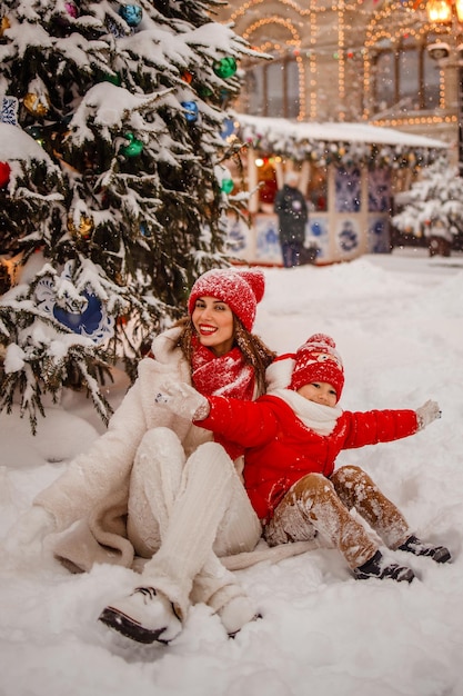 Mother and son in warm clothes have fun in winter at a snowy New Year's fair on Red Square in Moscow