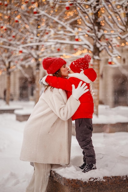 Mother and son in warm clothes have fun in winter at a snowy New Year's fair