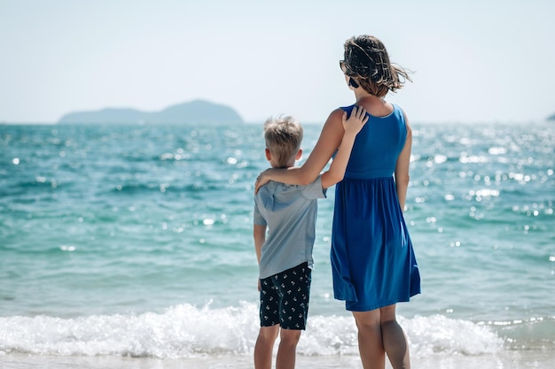 Mother and son watch the sea together. Mom holds hand of her child. Back view. Summer sea vacation concept. Phuket. Thailand. Beautiful sea