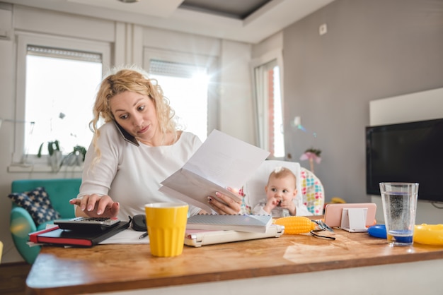 Photo mother talking on smart phone at home office