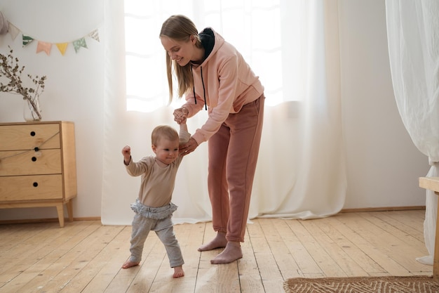 Mother teaching to walk her little baby Portrait of happy family at home first step concept