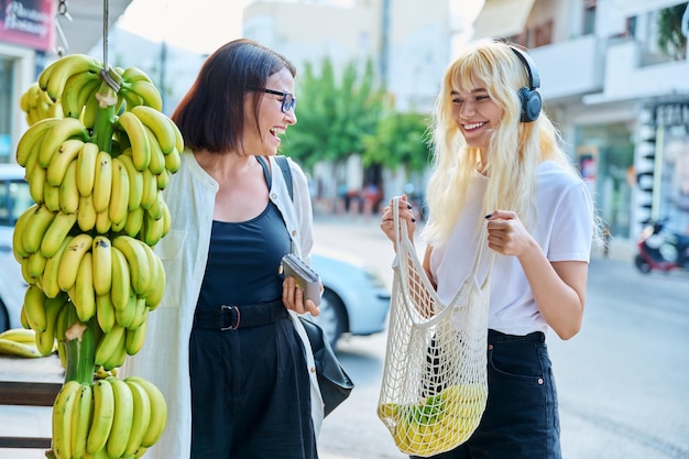 Mother and teenage daughter buying bananas at a street retail market