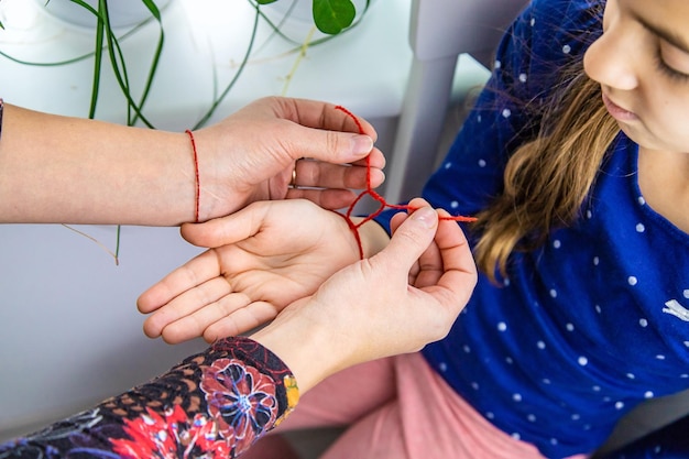 The mother ties a red thread to the child hand Selective focus