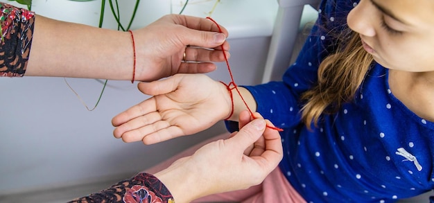 The mother ties a red thread to the child hand Selective focus