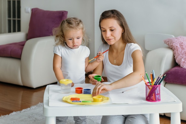 Mother and toddler child painting at home creative family