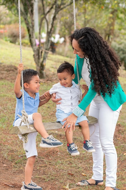 Mother and two children having fun on a swing in a natural park