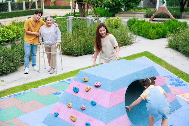 Mother and two kid fun running together while Father and grandmother looking for them play at playground