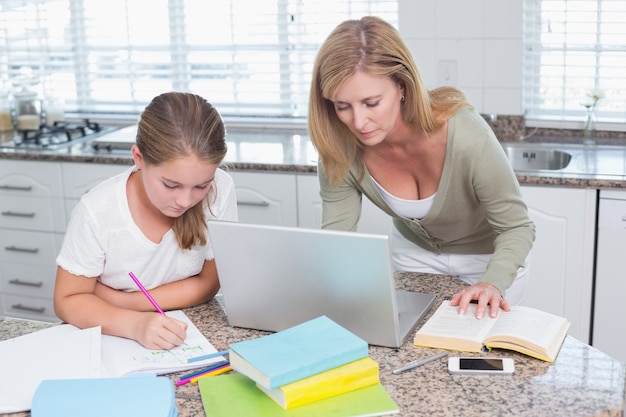 Mother using laptop while daughter doing homework 