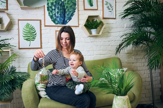 Mother with an 1 year old baby sitting on a sofa at home