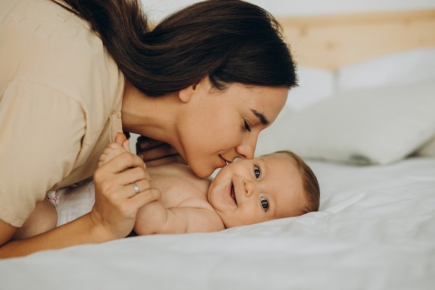 Mother with baby daughter lying on bed