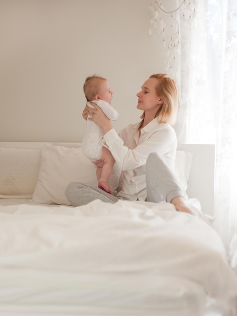 Mother with a child at white bedroom small baby boy with mom mathernity and childhood