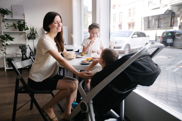 Mother with children drinking hot chocolate and latte at a local coffee shop. They are smiling and having fun. Motherhood concept