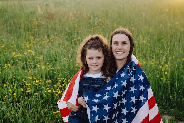 mother with daughter kid wrapped in american flag