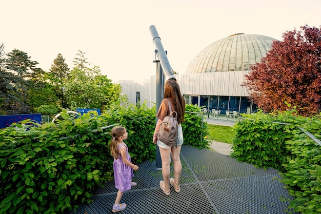 Mother with daughter at observatory looking in telescope outdoor