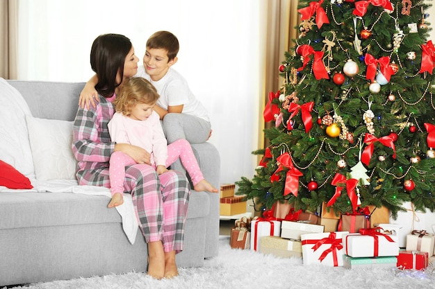 Mother with daughter and son near Christmas tree