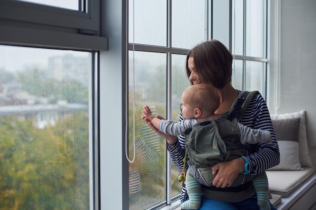 Mother with ergobaby carrying toddler at home