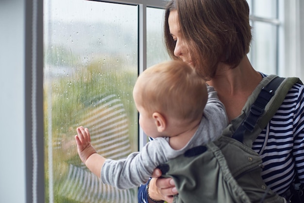 Mother with ergobaby carrying toddler at home